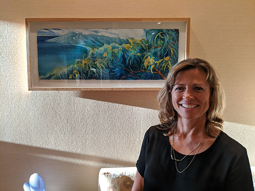 Maui artist Christine Waara stands in front of her original koa watercolor painting at the spa at the Fairmont Kea Lani hotel in Maui